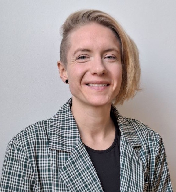 A friendly smiling person wearing a green ginham blazer